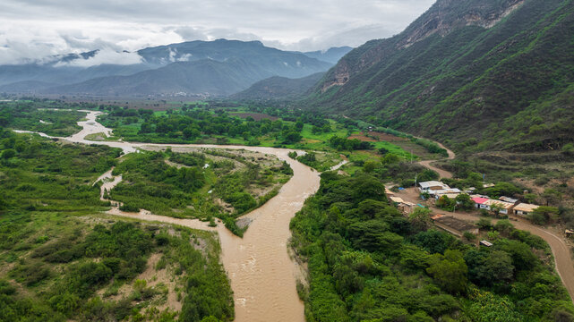 Aerial view of La Leche River winding through green valley with rice fields and mountains in Lambayeque Peru