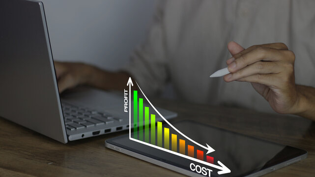 Profit and cost analysis concept showing a businessman tracking a downward cost trend on a tablet to visualize expense reduction, financial efficiency, and maximized profit margins