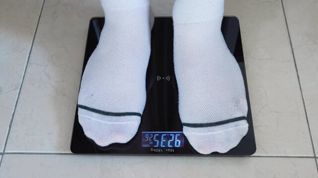 A person stepping on a smart digital scale