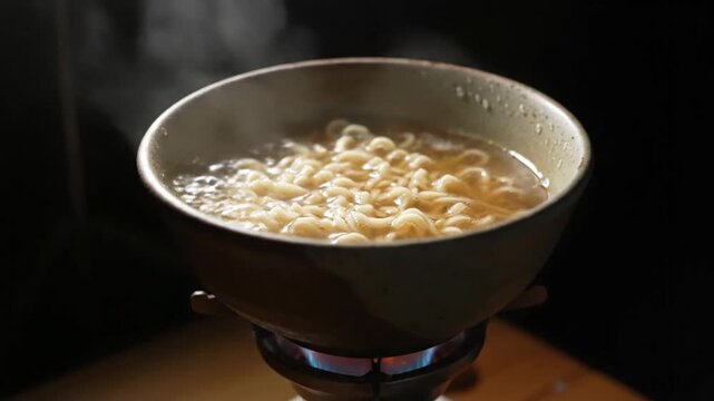 Steaming hot bowl of instant noodles cooking in boiling water on a gas stove, a culinary delight