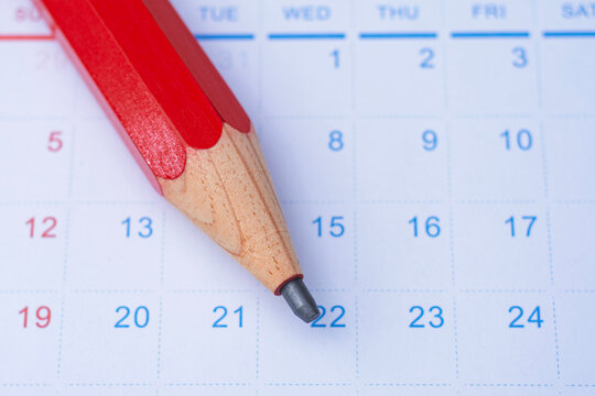 Close up of red pencil lying on monthly calendar with dates area. Concept planning, appointment reminder and organizing time and schedule. Time management articles and event planning.