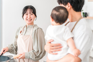 Obraz premium A couple in aprons holding their baby in the kitchen, a family