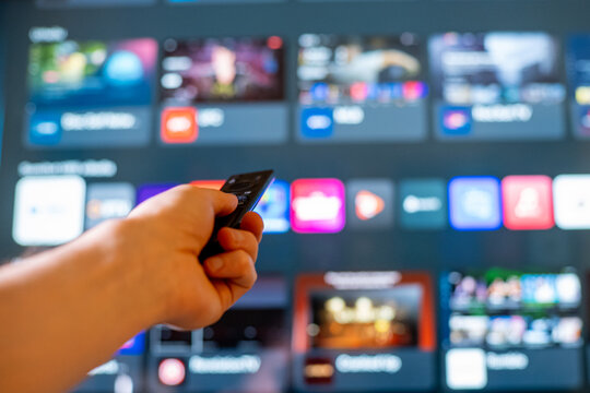 Hand Holding Remote Control Toward Smart TV Streaming Menu