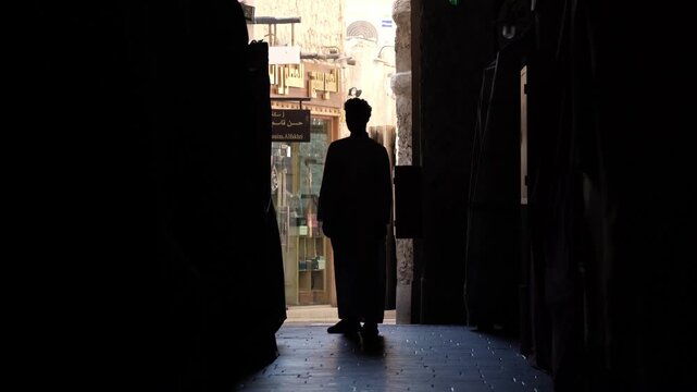 Silhouette of man walking through traditional alley in Middle East