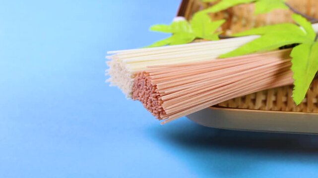 水色背景で回転するザルの上のカラフルそうめん