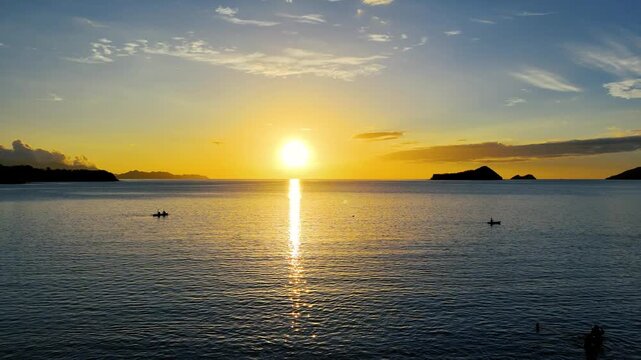 Amanecer dorado cinematogr&aacute;fico sobre el oc&eacute;ano Pac&iacute;fico con botes en el horizonte, toma a&eacute;rea de drone en Costa Rica.