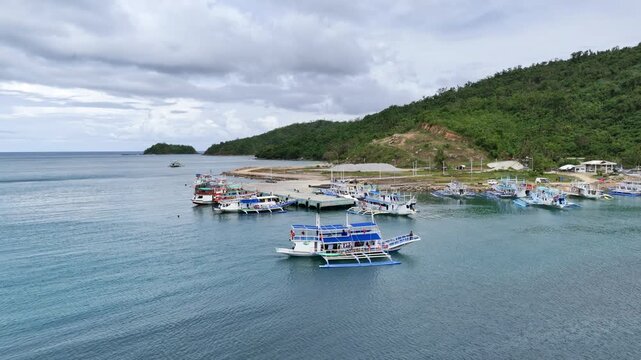 Tracking drone shot of an expedition outrigger boat slowly moving to line up at San Fernando Port, Philippines