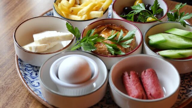 Turkish breakfast platter featuring fried potatoes eggs sausages cheese and fresh cucumber.