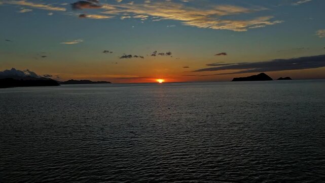 Atardecer cinematogr&aacute;fico con siluetas de monta&ntilde;as y bote de pesca en el oc&eacute;ano Pac&iacute;fico, toma a&eacute;rea de drone en Costa Rica.