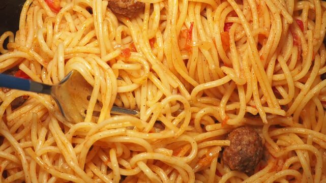 Close up motion of fork twirling spaghetti and meatballs in tomato sauce.