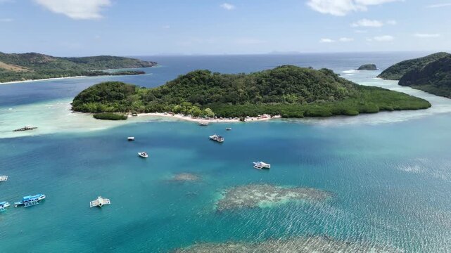 Establishing pull-away drone shot of Maapdit Island surrounded by turquoise waters in Linapacan, Palawan, Philippines