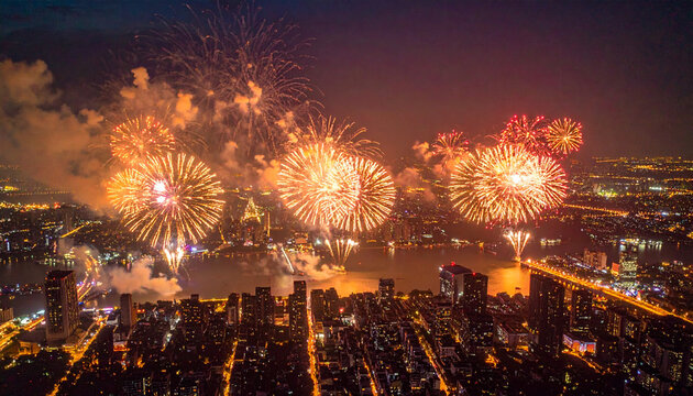 大河沿いの夜景と黄金色の花火が広がる祭典の空撮全景