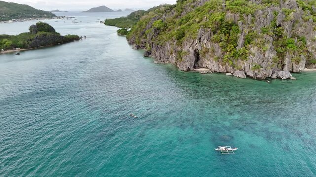 POI drone shot of local fishermen fishing near the island coast of Linapacan, surrounded by clear turquoise waters and shallow reef areas, Philippines
