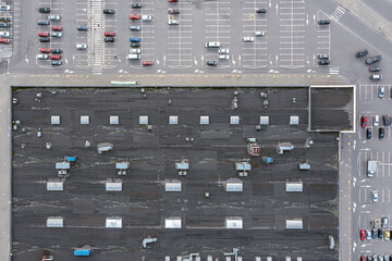 shopping mall shingle roof with ventilation system and skylights. parking lot with parked cars. aerial top view.