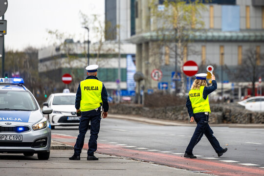 Warsaw, Poland - April 04, 2026: Polish police officers in high-visibility vests standing by a patrol car with flashing lights during a road safety operation