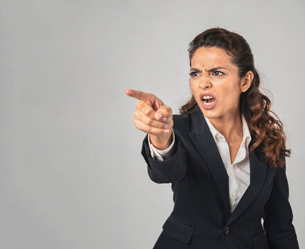 Angry businesswoman pointing and looking shocked.