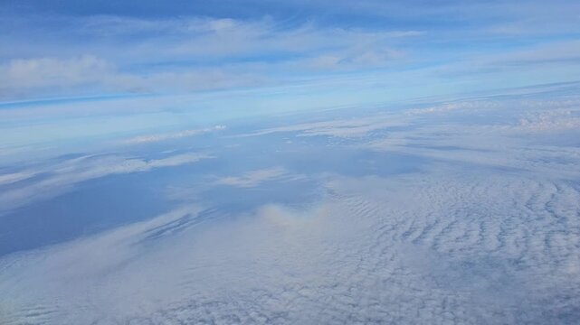 Spectacular high-altitude video from an airplane window showing a vast expanse of white clouds beneath a deep blue sky over the Andaman region.