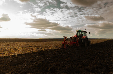 Tractor plowing field the land at sunset