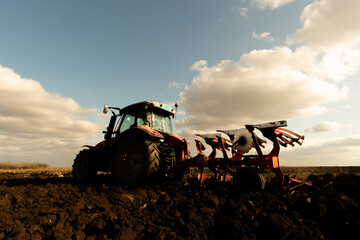 Tractor plowing field the land at sunset