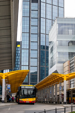 Warsaw, Poland - April 04, 2026: A yellow city bus at a stop near the Warsaw Central Railway Station with modern skyscrapers in the background