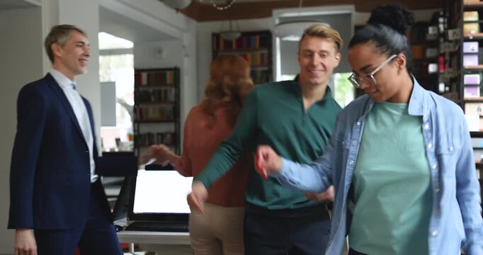 Active multiethnic office employees having fun, dancing together during break, moving to music in workplace. Staff members relieve stress, celebrating victory. Work life balance, friendly team bonding