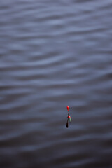 Red fishing float bobbing on dark rippled water © k49red