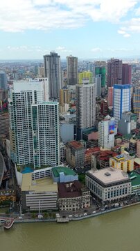 Aerial drone view of Manila skyline with high-rise buildings along Pasig River. Dense urban cityscape of Philippines capital with modern architecture and waterfront.