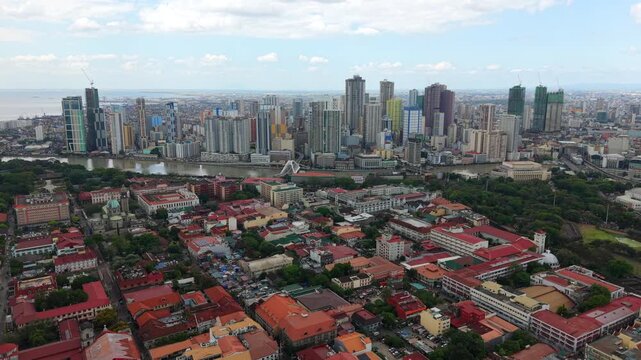 Aerial drone view of Manila skyline with Intramuros historic district in the foreground. Contrast between old colonial architecture and modern cityscape in Philippines capital.