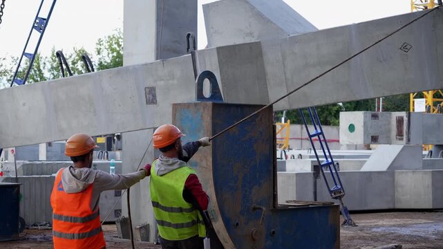 Construction workers pulling concrete structure with rope