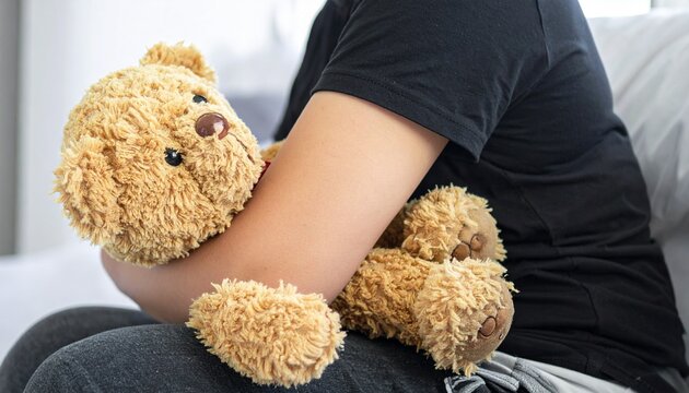 すわりながらクマのぬいぐるみを抱える女性の写真