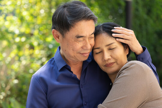 Happy smiling lovely Asian senior couple, elderly husband and wife hugging each other in urban park with good quality of life togetherness after retirement, real human, real people model