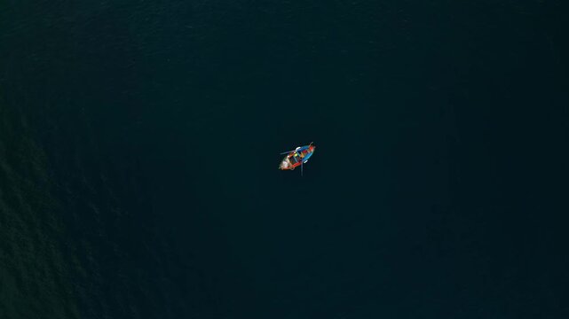 Fishing boat with crew navigating through calm waters, showcasing the serene environment and the rhythmic motion of oars against the water surface