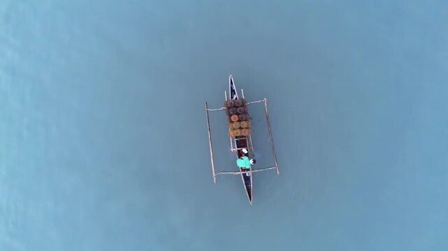 Bird's eye static drone shot over a local fisherman on his small outrigger boat retrieving crab traps at Malampaya Inner Sound, Philippines