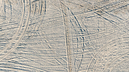 Aerial view tire tracks on sandy beach, Tire tracks on the sand surface texture background, Tire tracks curve across the soft sand, Wheel tire track on sand texture and background.