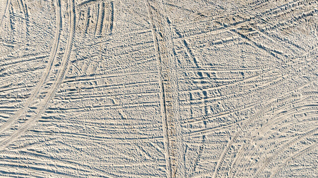 Aerial view tire tracks on sandy beach, Tire tracks on the sand  surface texture background, Tire tracks curve across the soft sand, Wheel tire track on sand texture and background.
