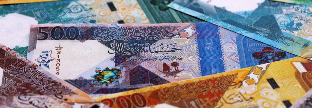 Qatari riyal money bills pile on table. Qatar banknotes of QAR currency close up.
