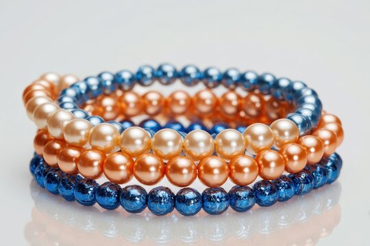 Minimalist fashion bracelets on white backdrop: elastic pearl bead bracelets in warm orange and cool blue with a metallic blue accent