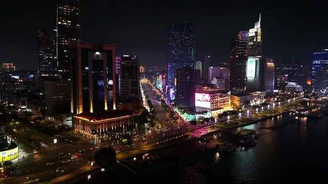 Cinematic aerial drone flying along Ton Duc Thang street with traffic flow and Saigon riverside night cityscape