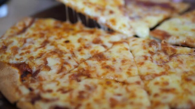 Close-up of hand lifting a slice of thin crust pizza with hot melting cheese pull on wooden board for restaurant advertisement