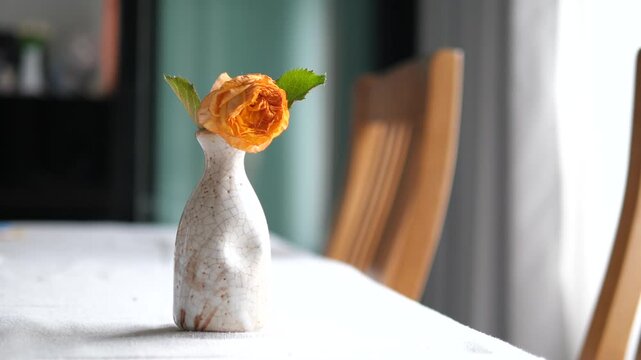 Vertical close-up of withered orange rose in a ceramic vase representing sadness ending and fading memories concept