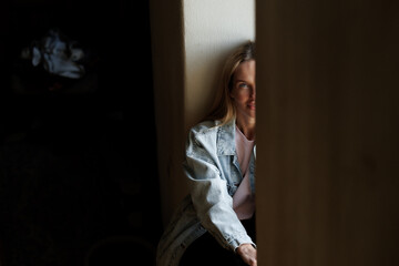 Fototapeta premium Young woman sitting by window in natural light with copy space, calm lifestyle portrait indoors