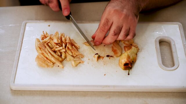 Slicing apples on a cutting board with a knife in a kitchen area