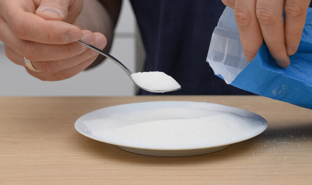 White loose sugar crystals close-up on a spoon, sweetened
