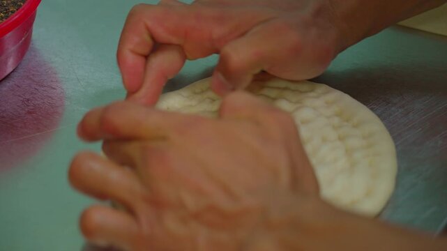 Chef shaping raw Uzbek flatbread, lyepeshka, before baking, close-up