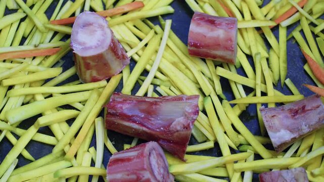 Close-up of sliced yellow carrots with raw marrow bones in empty kazan for Uzbek plov