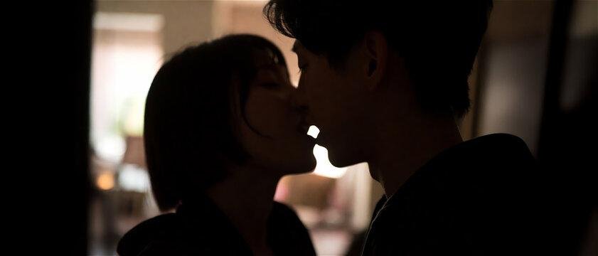 Silhouette couple passionate kiss dramatic backlighting intimate embrace romantic mood dark background close up