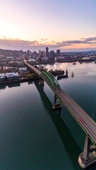 Obraz premium A picturesque aerial view captures a long bridge spanning a waterway at dawn. The city skyline sits in the backdrop