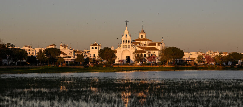 El Roco Hermitage glowing softly at dawn over calm waters