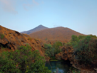 Wadi Sahalnoot, scenic landscape with canyon filled with fresh water among the mountains in Salalah, Oman at sunset