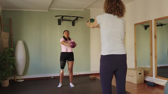 Amputee woman training with personal fitness instructor at home gym